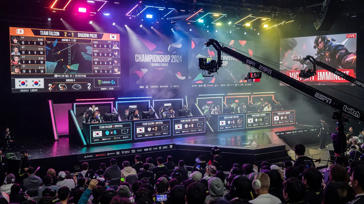 Wide tournament stage with multiple booths, audience and broadcast cameras